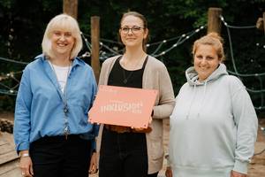 3 Mitarbeiterinnen präsentieren eine Plakette